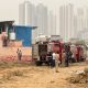 Gurgaon Factory Blast - Firefighters and authorities inspect the aftermath of an explosion at a factory site in Gurgaon, with high-rise buildings in the background.