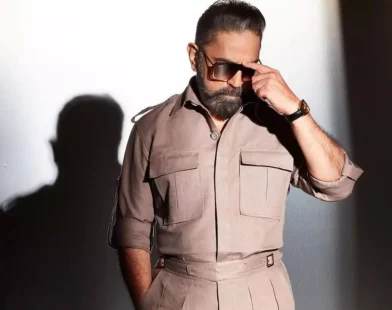 Actor in a beige outfit and sunglasses posing for a promotional photo for Indian 2.