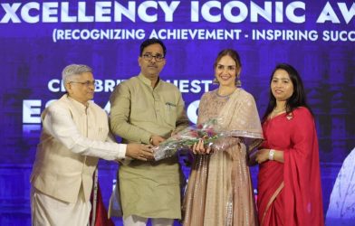 Four individuals standing on a stage during an award ceremony, with one person handing a bouquet to another at Bizz Expo & Summit .