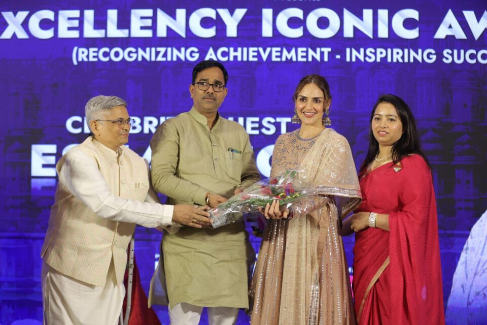 Four individuals standing on a stage during an award ceremony, with one person handing a bouquet to another at Bizz Expo & Summit .