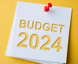 A white note with "BUDGET 2024" written in bold letters and pinned to a yellow background.