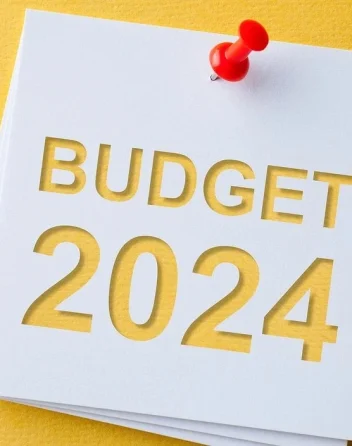 A white note with "BUDGET 2024" written in bold letters and pinned to a yellow background.